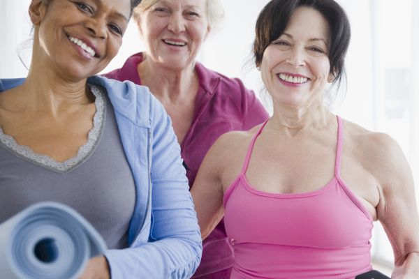 Three smiling women with exercise equipment.