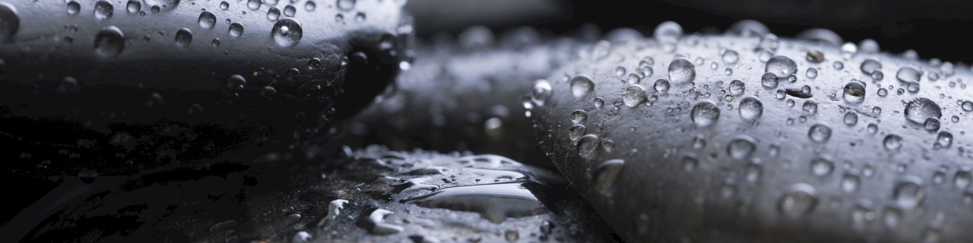 Smooth wet stones with water droplets, likely depicting a tranquil scene.