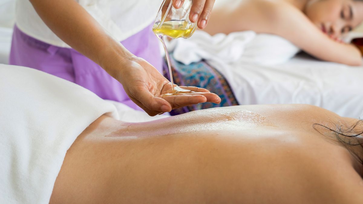 A person is receiving a massage with oil being poured on their back.