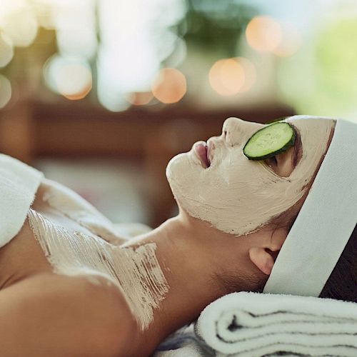 A person is relaxing with a face mask and cucumber slices on their eyes.