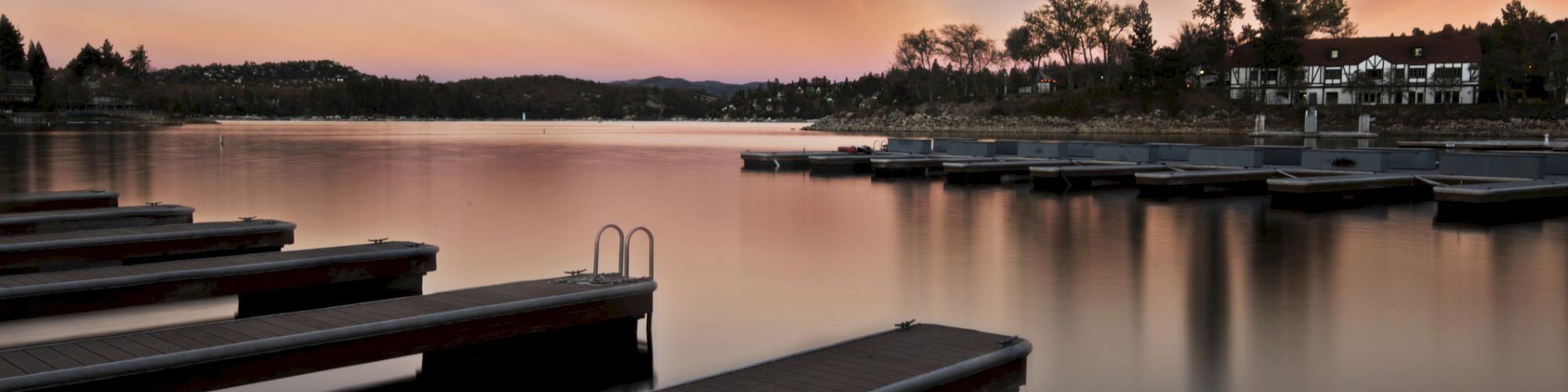 A serene lake at dusk with striking crepuscular rays, empty docks in the foreground, and tranquil scenery.