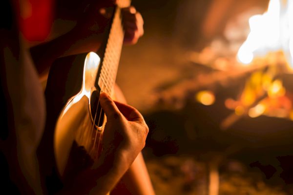 Someone is playing guitar by a warm campfire.