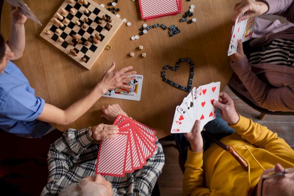 People are playing cards and a game of chess is also laid out on the table.