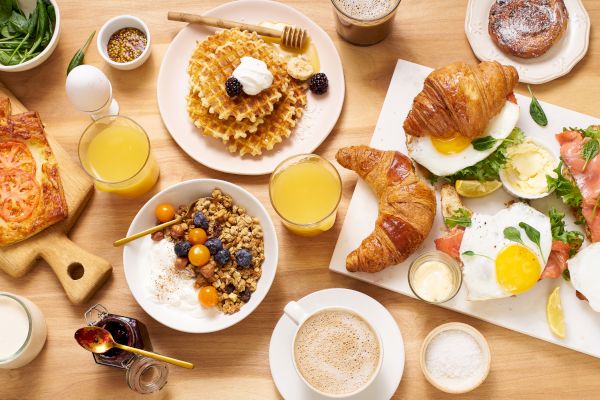 A delicious breakfast spread with waffles, croissants, eggs, and coffee.