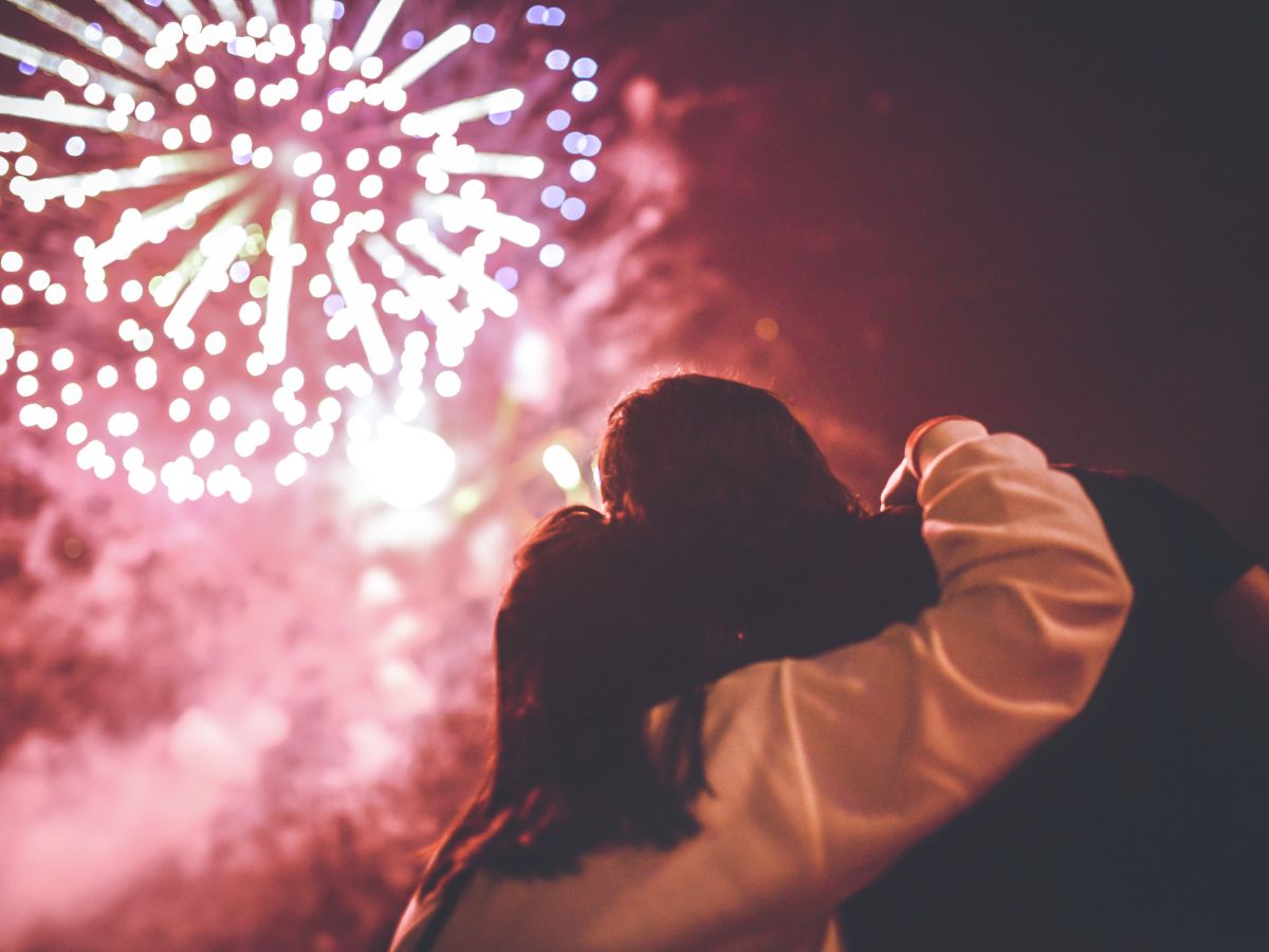 Two people are watching fireworks light up the sky.