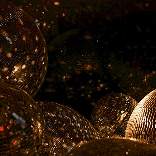 The image shows several disco balls reflecting light in a dark setting, creating a sparkling and festive atmosphere.