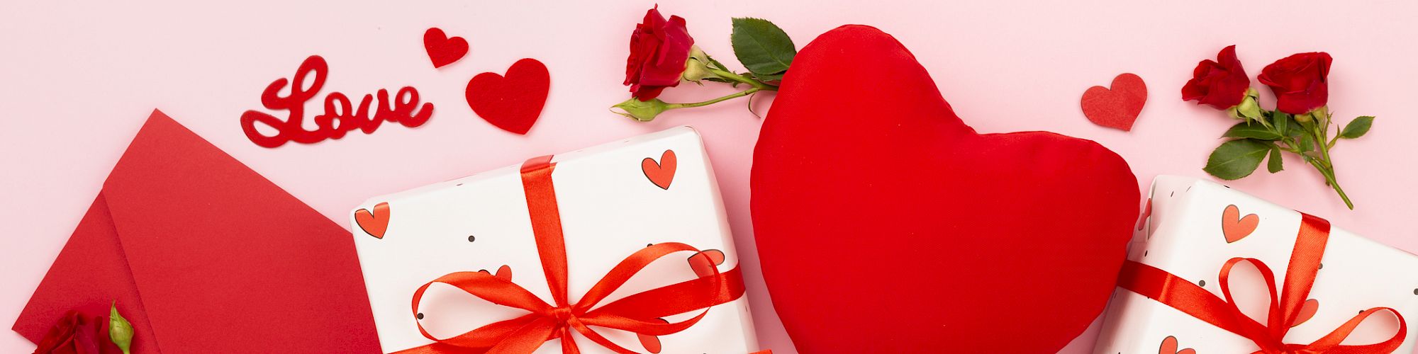 The image shows a love-themed arrangement with a heart pillow, red envelope, roses, gifts with red bows, and the word "Love" on a pink background.