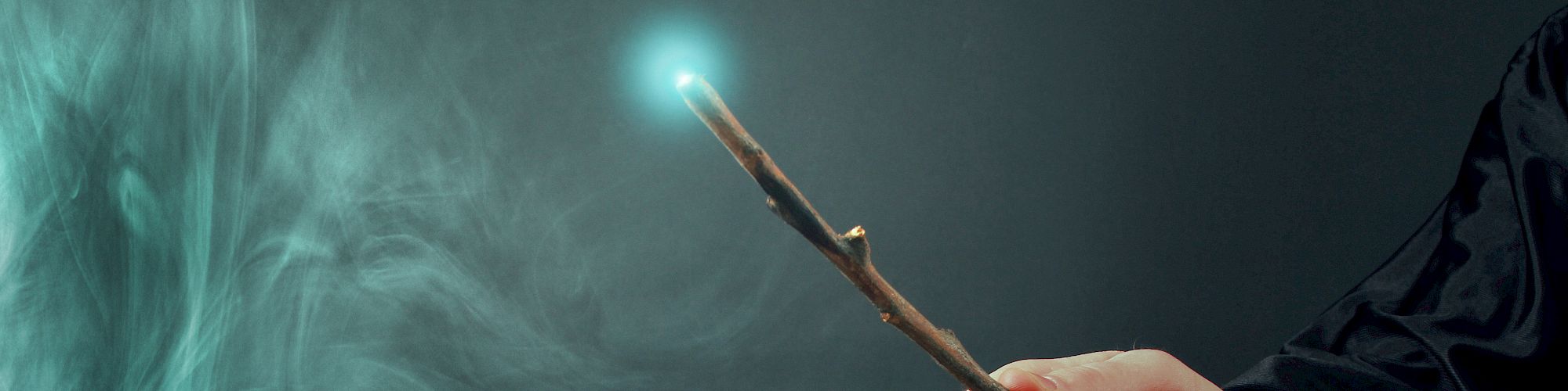 A hand holding a wand with a glowing tip, emitting a light swirl in a dark setting.